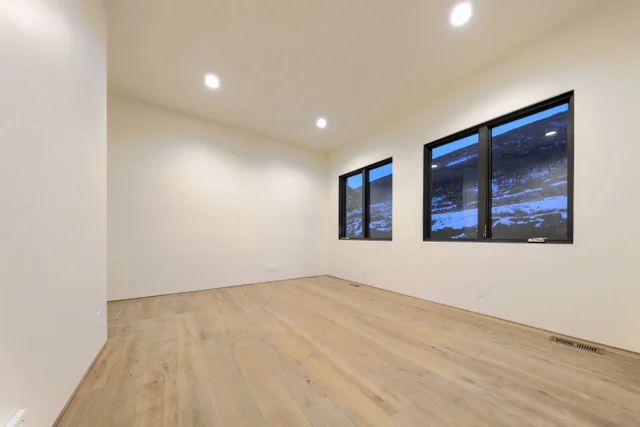 Bedroom with hardwood floors, black windows, and mountain views in Deer Mountain custom home, Park City