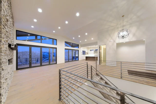 Open main level with stone wall, chandelier, and kitchen in Deer Mountain custom home, Park City