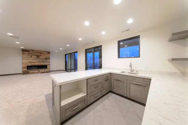 Basement wet bar with reclaimed wood fireplace surround in Deer Mountain custom home, Park City
