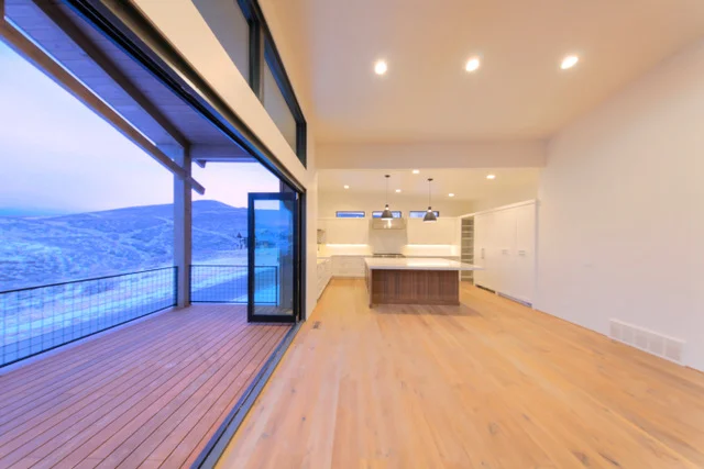 Kitchen viewed from living area with open sliders to deck in Deer Mountain custom home, Park City
