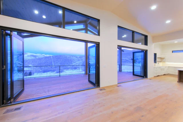 Great room with open doors to deck and high ceilings in Deer Mountain custom home, Park City