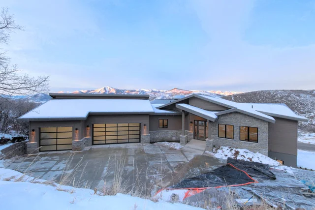 Front exterior daytime view with stone accents and three-car garage in Deer Mountain custom home, Park City
