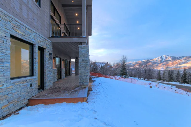 Lower level walkout with stone wall and upper deck in Deer Mountain custom home, Park City