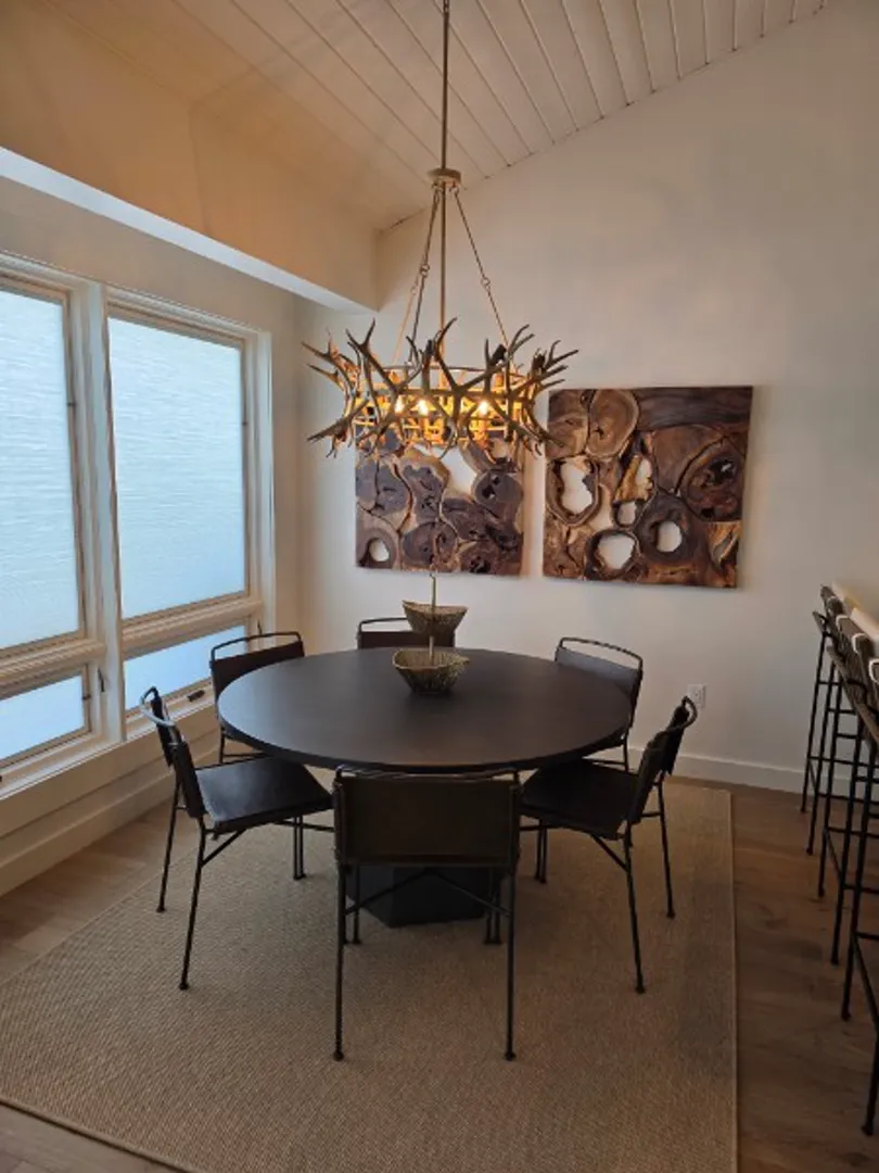 Dining area with round table, antler chandelier, and vaulted ceiling in Deer Valley remodel