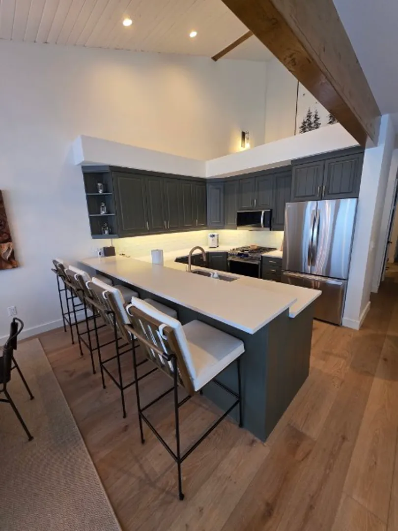 Kitchen with dark cabinets, white quartz bar, and wood beams in Deer Valley
