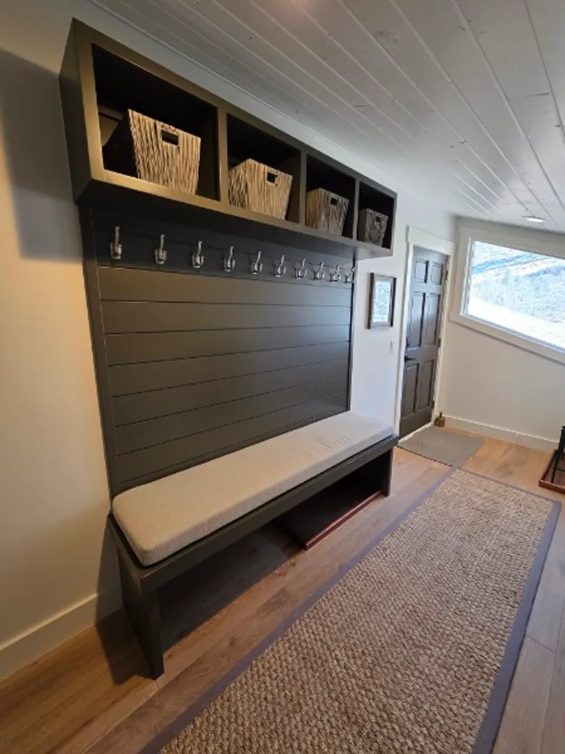 Mudroom entryway with built-in bench, storage cubbies, and coat hooks in Deer Valley remodel