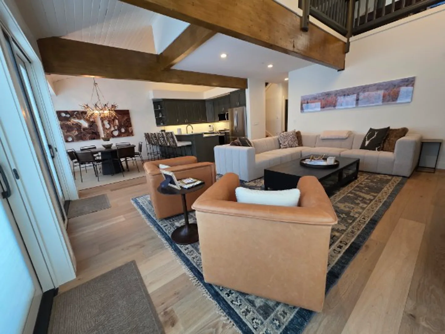 Open concept living, dining, and kitchen area with exposed wood beams and vaulted ceiling in Deer Valley remodel