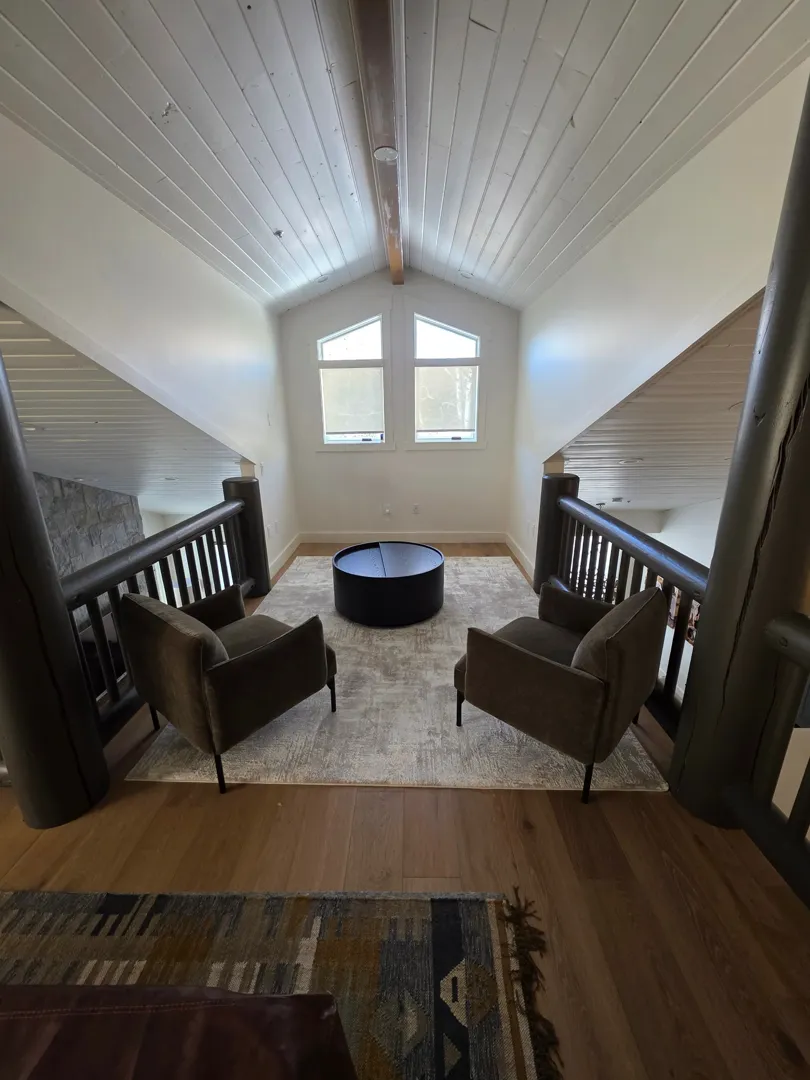 Upper loft seating area with vaulted ceiling and peaked windows in Deer Valley remodel