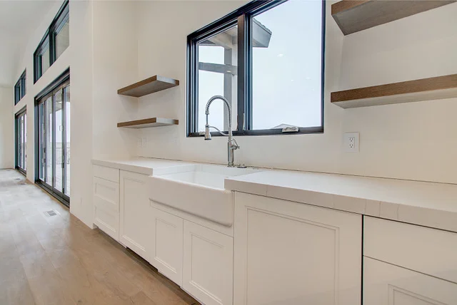 Farmhouse sink detail with commercial faucet and floating shelves in Park City custom kitchen