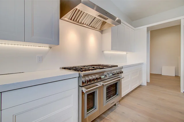 Professional range with custom hood and white shaker cabinets in Slalom Run kitchen