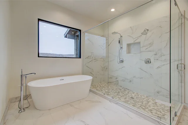 Master bath freestanding tub with large marble shower and pebble floor in Slalom Run home