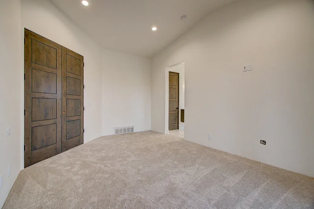Carpeted bedroom with rustic wood closet doors in Park City custom home
