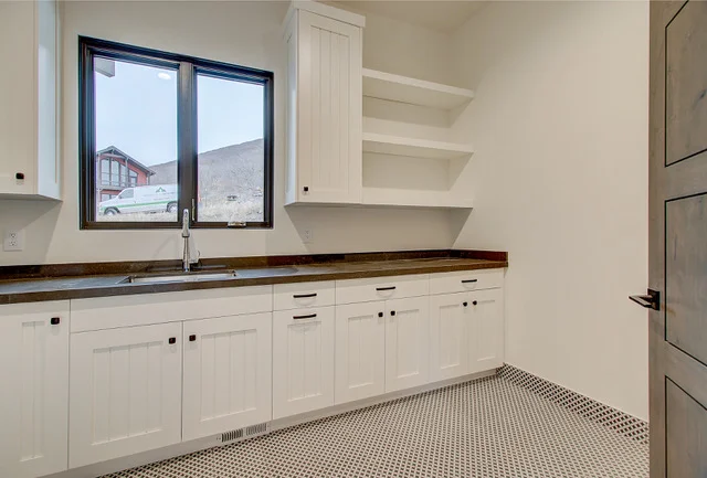 Laundry room alternate angle with shelving and dark counter in Park City home