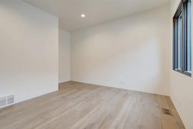 Minimal guest bedroom with hardwood floors in Slalom Run custom home