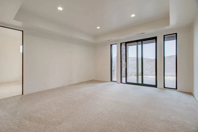Carpeted master bedroom with tray ceiling and sliders to deck in Park City luxury home
