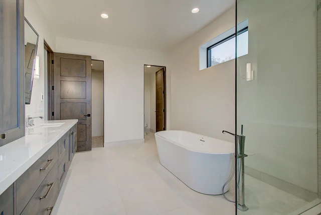Bathroom with dark wood vanity, freestanding tub, and glass shower in Slalom Run home