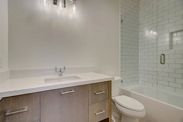 Guest bath with single vanity, subway tile tub shower, and glass door in Park City