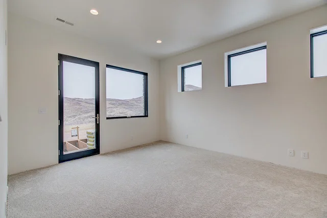 Lower level carpeted bedroom with glass door to patio in Park City custom home