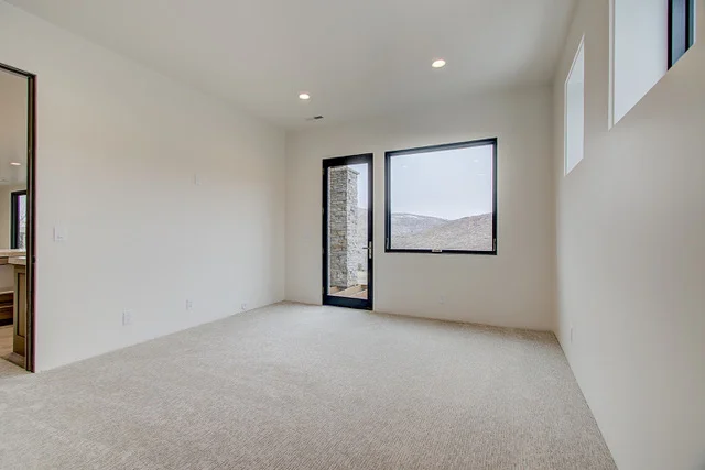 Carpeted bedroom with glass door to patio and mountain views in Park City