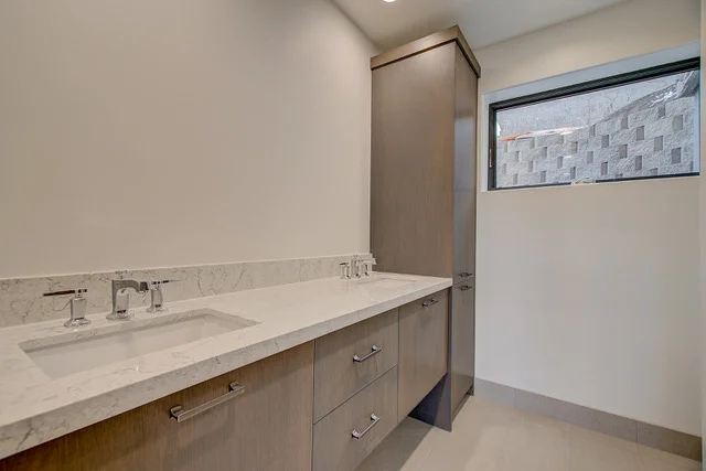 Bathroom dual vanity with quartz countertop and marble backsplash in Slalom Run home