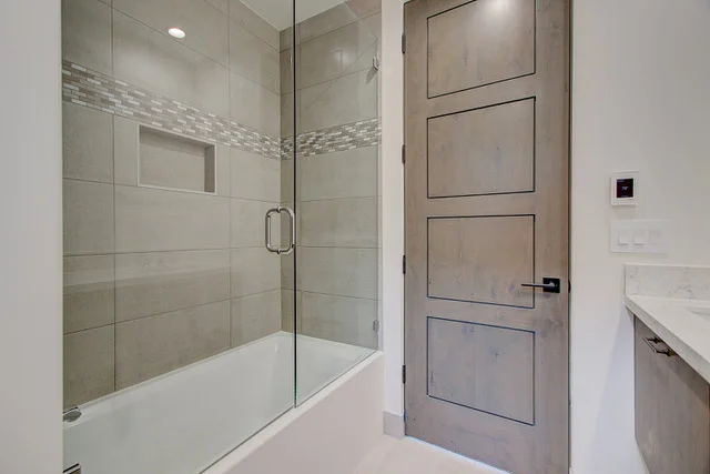 Bathroom tub shower with glass door and decorative tile band in Park City custom home