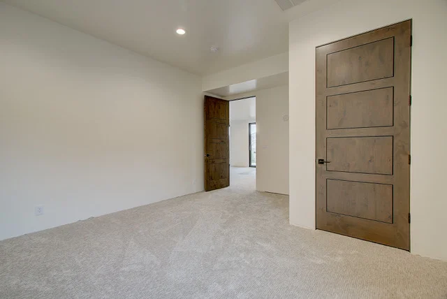 Carpeted bedroom with rustic wood doors in Park City luxury home