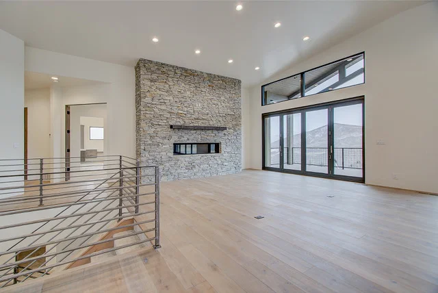 Great room with stone fireplace, metal stair railing, and sliding doors in Slalom Run