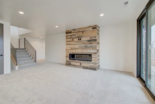 Basement family room with reclaimed wood fireplace and staircase in Park City home