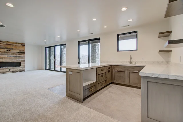 Basement wide view with wet bar, reclaimed wood fireplace, and sliding doors in Slalom Run