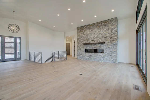 Great room with stone fireplace, orb chandelier, and front doors in Slalom Run luxury home