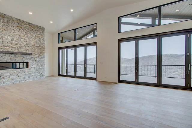 Great room with stone fireplace, floor-to-ceiling sliders, and mountain views in Park City