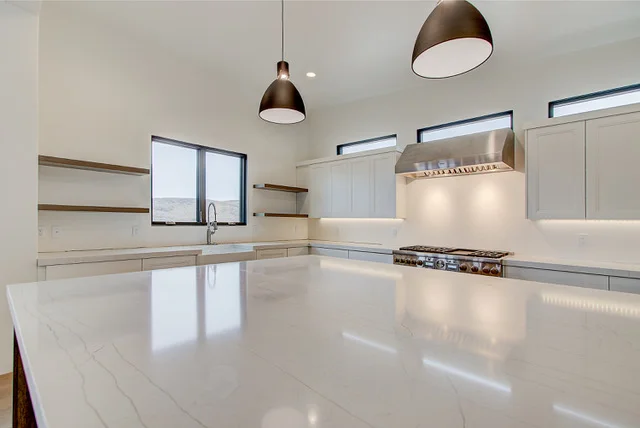 Kitchen with large quartz island, pendant lights, and range hood in Slalom Run custom home