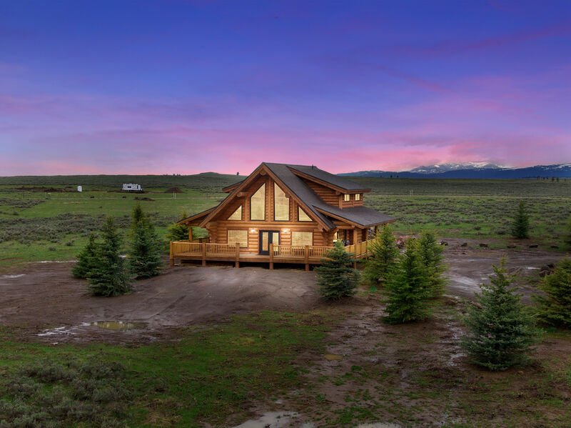 Custom log home glowing beneath a pink and blue mountain sunset