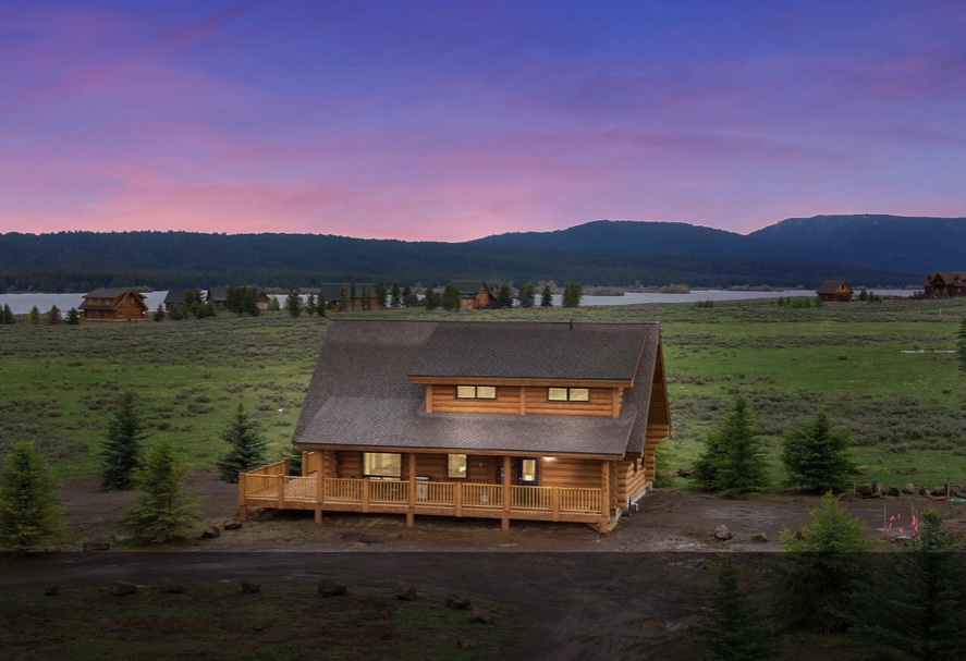 Finished custom log home exterior set against a mountain landscape